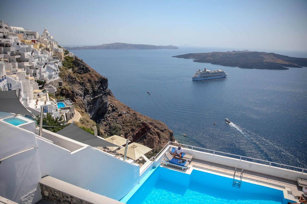 Grécia cria taxa para cruzeiros em Santorini e Mykonos e controla turismo excessivo Navios de cruzeiro e piscinas com vista para o mar, uma constante em Oia, na ilha de Santorini, na Grécia (Foto: Aris Oikonomou / AFP)