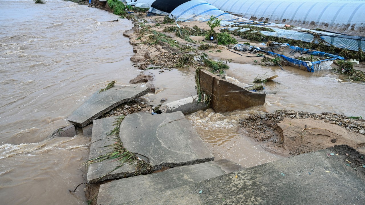 Uma estrada é levada pela chuva forte perto de um riacho em Galsan-Myeon, na província de Chungcheong do Sul, na Coreia do Sul. 17/07/2025 (Foto: Seung-il Ryu/NurPhoto/Getty Images)