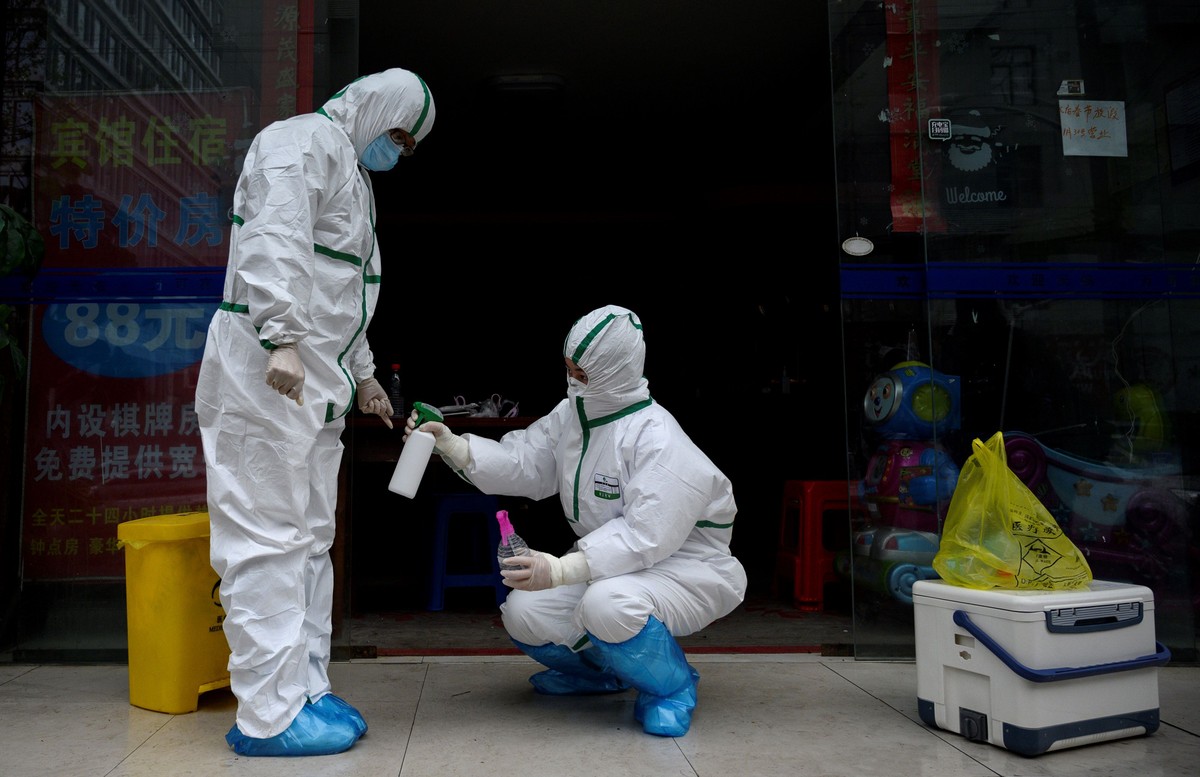 China investiga ex-prefeito de Wuhan por gestão da pandemia de Covid-19 Médico em traje de proteção desinfeta colega em clínica de teste para Covid-19 em Wuhan, na China (Foto: Noel Celis / AFP)