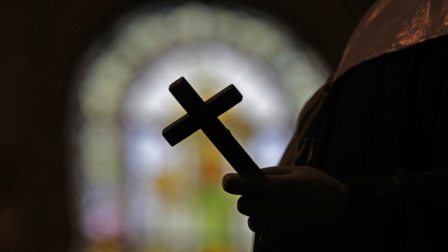 Um crucifixo é silhuetado contra uma janela de vitral dentro de uma igreja católica em Nova Orleans, 1 de dezembro de 2012. (Foto: AP Photo/Gerald Herbert, File)