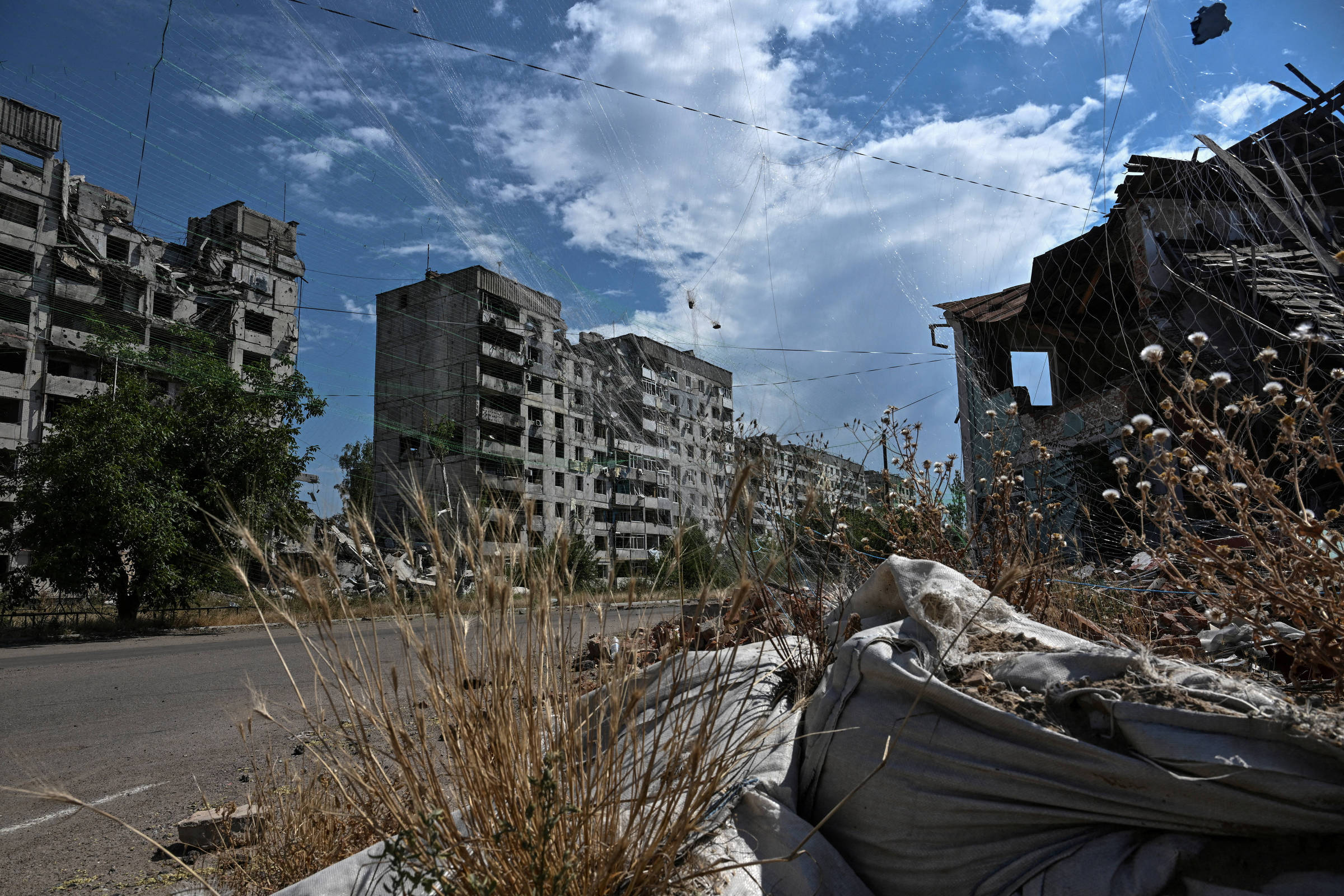 Ataque russo a prisão na Ucrânia resulta em 16 mortos e 35 feridos Prédio residencial danificado por ataques militares russos e redes antidrones instaladas sobre uma rua, na região de Zaporíjia (Foto: Stringer/Reuters)