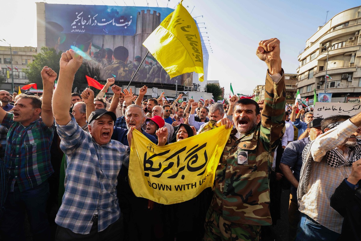 EUA intensificam tensões com ataque ao Irã e preocupações sobre guerra nuclear aumentam Iranianos com bandeiras contra Israel e EUA durante protesto em Teerã (Foto: ATTA KENARE / AFP)