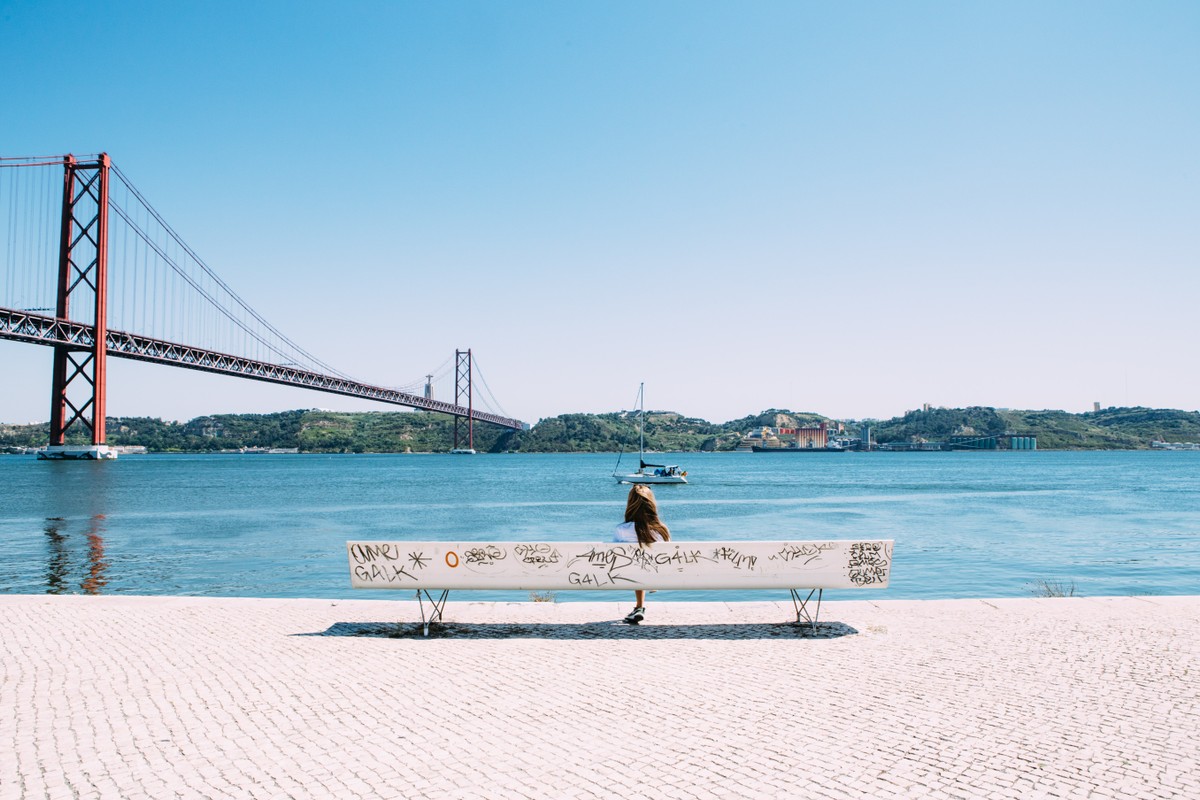Especialistas afirmam que reunir família imigrante em Portugal é solução positiva Mulher sentada em um banco à beira do Rio Tejo, em Lisboa (Foto: Jason Briscoe/Unsplash/Divulgação)