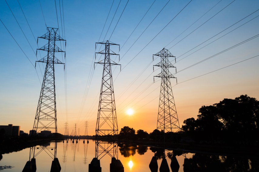 Califórnia será o primeiro estado dos EUA a usar IA para gerenciar apagões elétricos Torres de transmissão de energia e seus reflexos em um corpo d'água ao amanhecer - Yichuan Cao/Sipa USA via AP Images (Foto: Yichuan Cao/Sipa USA via AP Images)