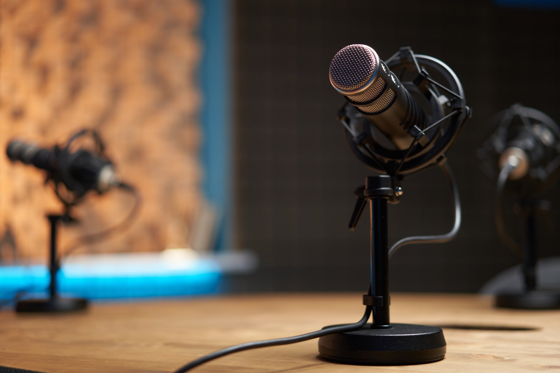 Milionários compartilham quatro hábitos que moldam líderes de sucesso Microfone moderno em foco suave colocado sobre uma mesa de madeira em estúdio de gravação durante um podcast (Foto: Sergey Mironov/Getty Images)