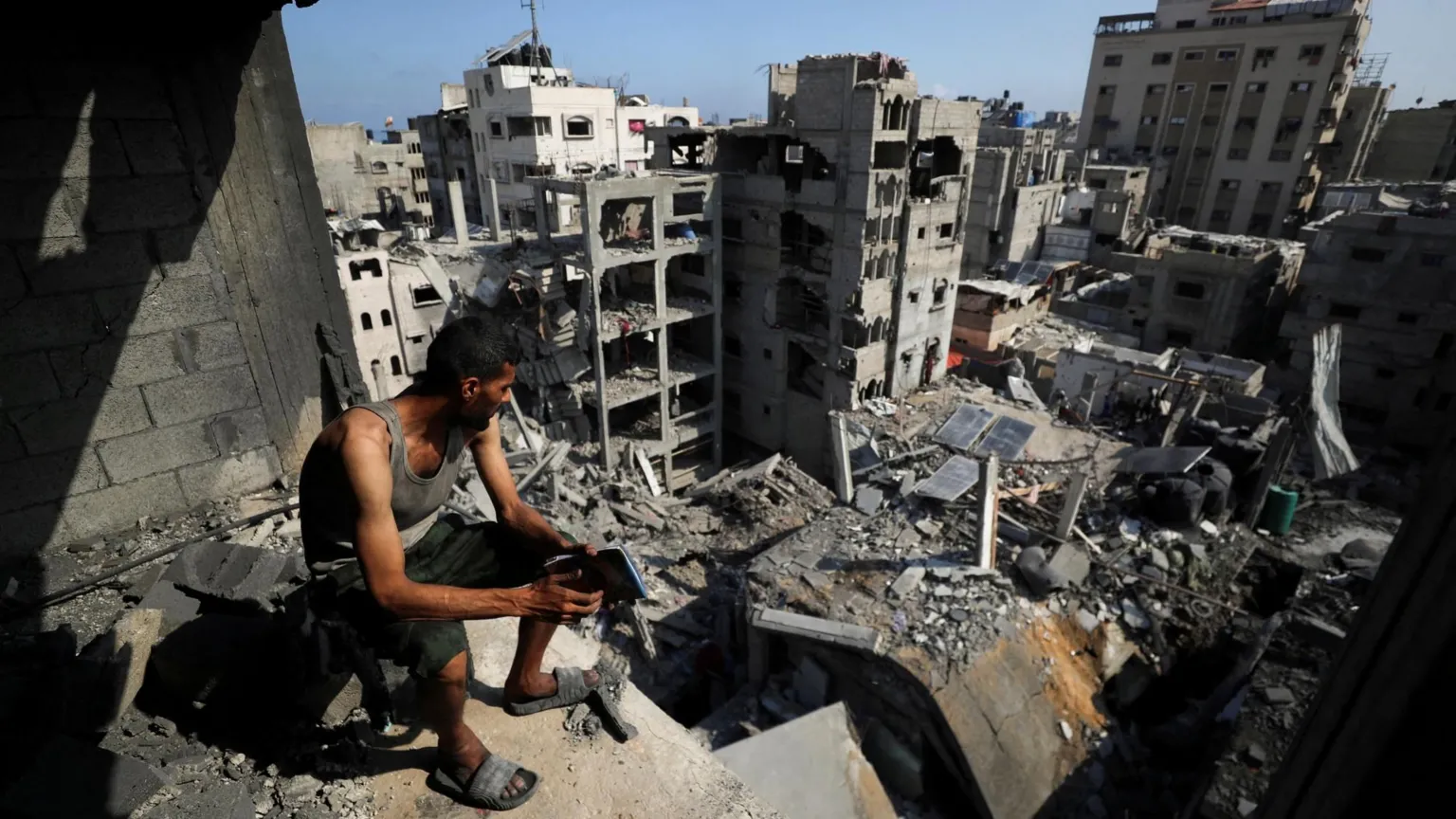 Hamas consulta grupos palestinos sobre plano de cessar-fogo em Gaza Um homem palestino observa prédios destruídos por ataques israelenses no campo de refugiados al-Shati, no norte da Gaza (Foto: Reuters)