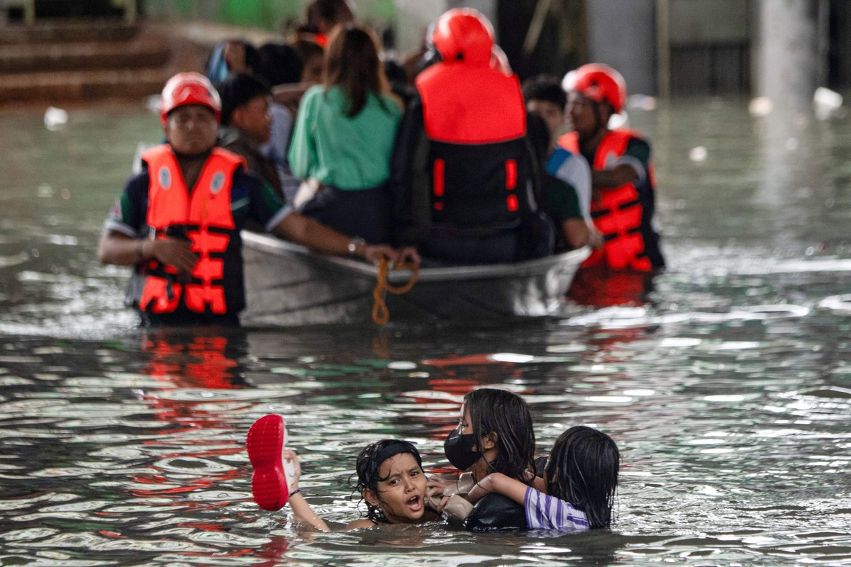 Tempestade Wipha causa mortes no Vietnã e cancela voos nas Filipinas Pessoas nadam em meio à enchente em uma rua de Manila (Foto: Ted ALJIBE / AFP)