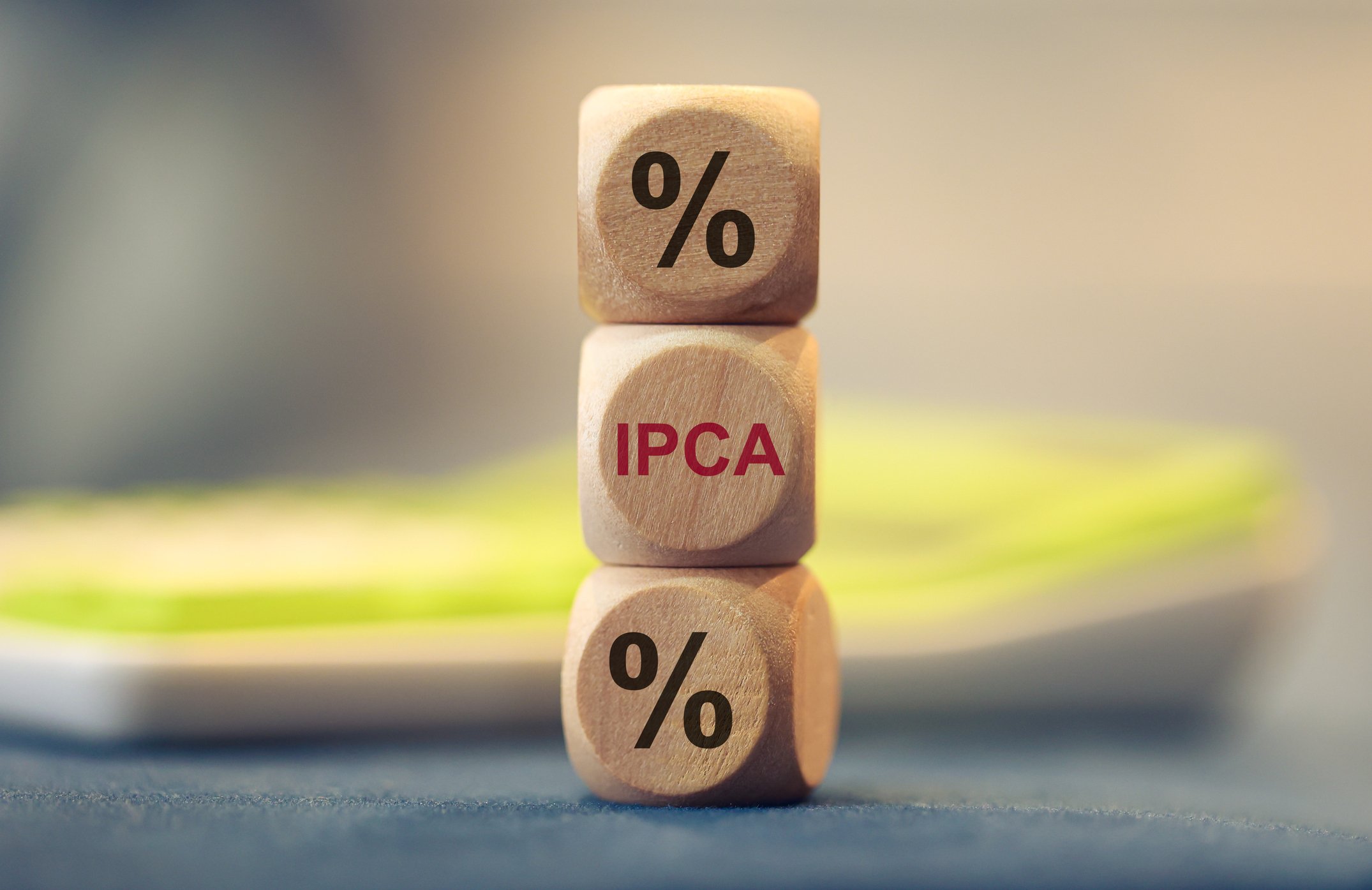 Mercado revisa projeção do IPCA para 2025 e espera leve queda no dólar Iniciais IPCA e o símbolo de porcentagem escritos em dados de madeira. (Foto: Rmcarvalho/Getty Images)