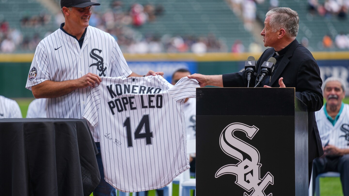 Cardeal Blase Cupich, à direita, apresenta ao ex-jogador do White Sox, Paul Konerko, uma camisa assinada pelo Papa Leão XIV durante uma cerimônia em homenagem aos campeões da World Series de 2005 antes de um jogo de beisebol entre o Cleveland Guardians e o Chicago White Sox, no sábado, 12 de julho de 2025, em Chicago. (Foto: AP Photo/Erin Hooley)