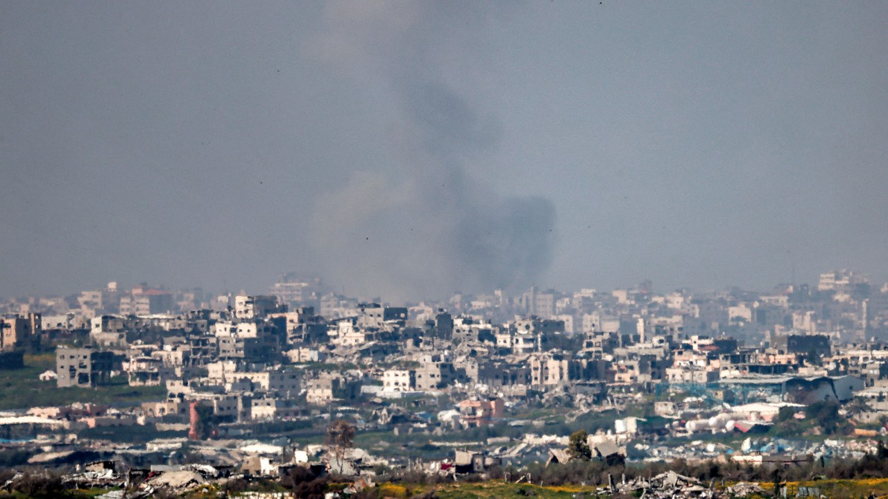Uma nuvem de fumaça em meio a prédios destruídos no norte da Faixa de Gaza, vistos do outro lado da fronteira, no sul de Israel. 18/03/2025 (Foto: Menahem Kahana/AFP)