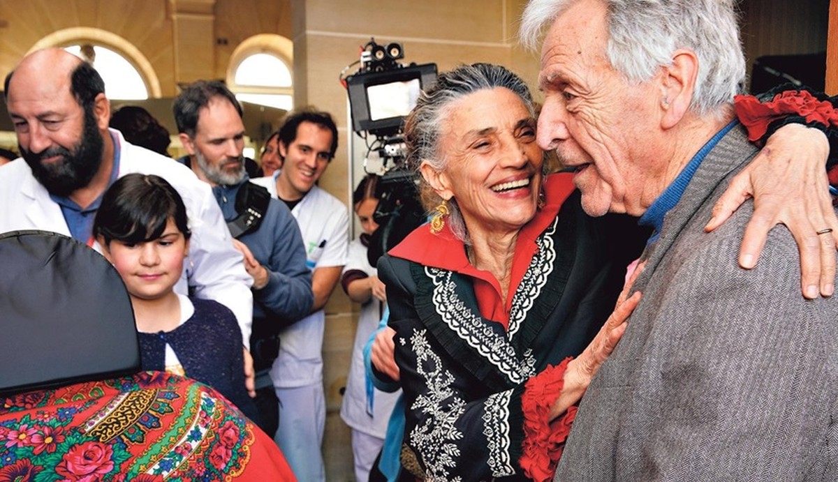 Costa-Gavras explora a morte com sensibilidade em novo filme aos 92 anos Uma família de ciganos se despede da matriarca cantando e dançando para ela, que é vivida por Angela Molina, na foto com Costa-Gavras (Foto: Divulgação)