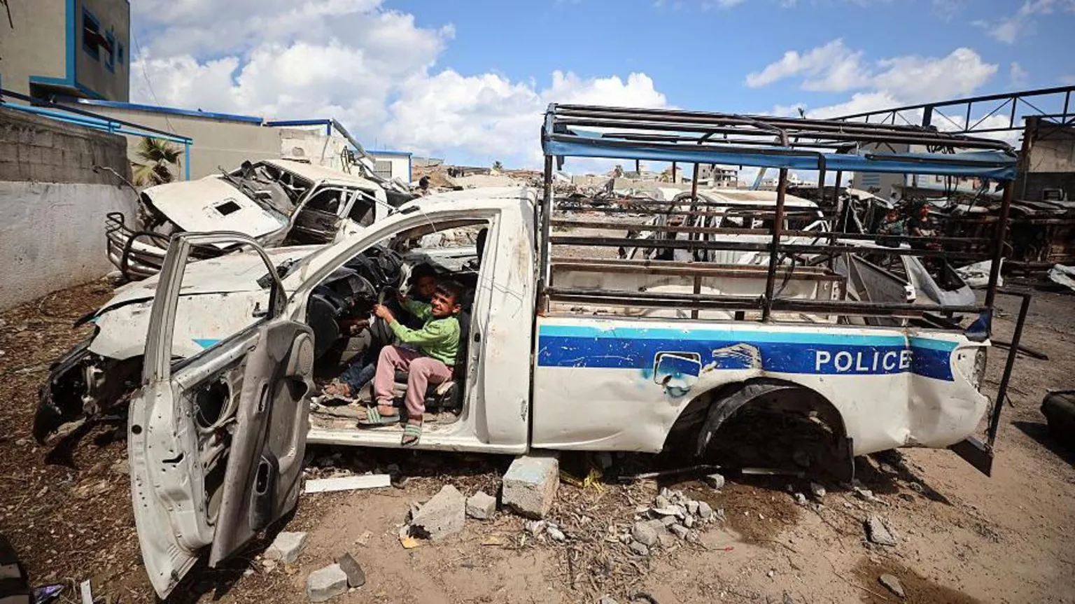 Uma criança deslocada brinca dentro de um veículo destruído na Academia de Polícia Arafat, na Cidade de Gaza (Foto: NurPhoto via Getty Images)