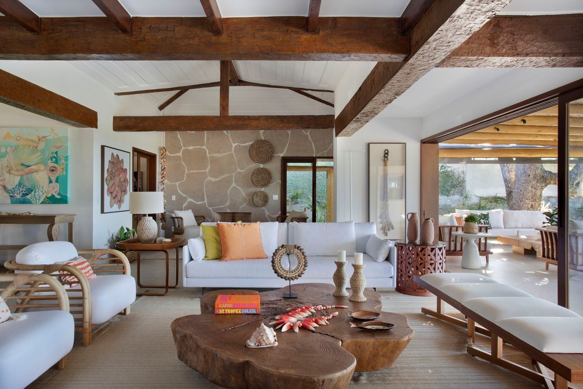 Casa de Brigitte Bardot em Búzios é reformada mantendo sua arquitetura original SALA DE ESTAR | O ambiente é composto por sofás, mesa lateral (à esquerda), par de bancos e mesa de centro de tronco de árvore, todos da Breton. Abajur do Studio Grabowsky. Tapete da Trama (Foto: MCA Estúdio/Divulgação)