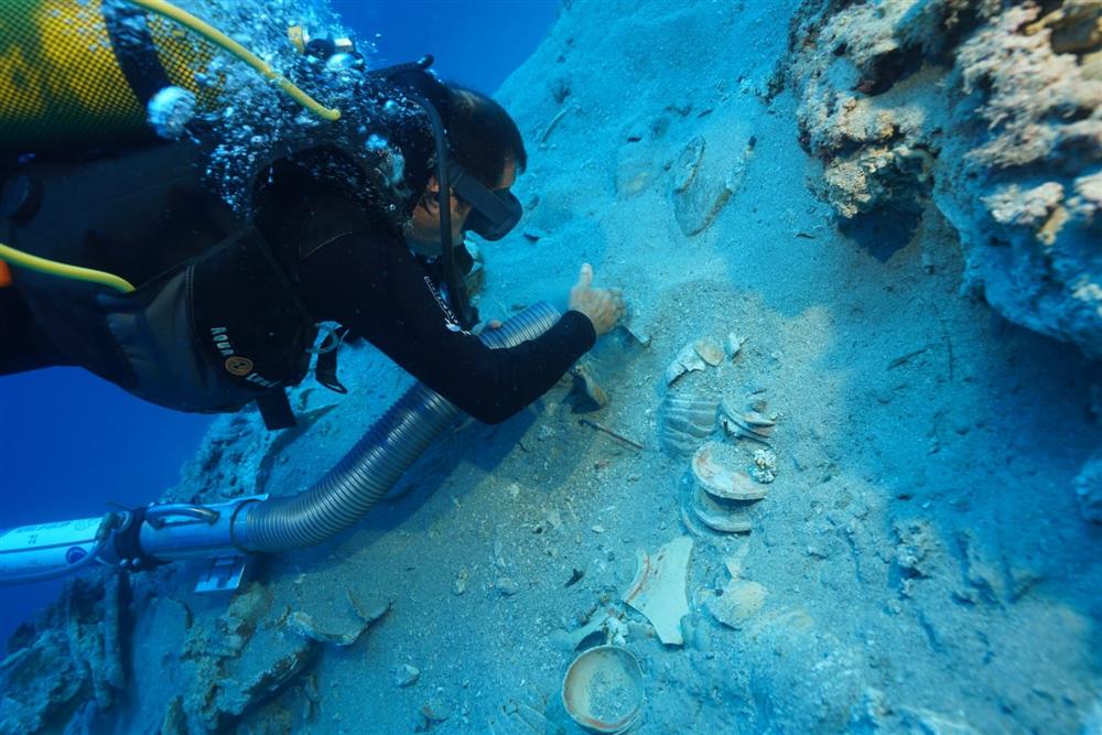 Descobertos centenas de artefatos cerâmicos em naufrágio preservado na Turquia Um mergulhador cuidadosamente escova a areia de cerâmicas empilhadas encontradas em um naufrágio ao largo da costa da Turquia. (Foto: Ministério da Cultura e Turismo, Turquia)