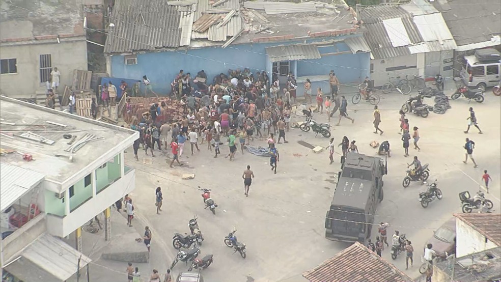 Multidão avança sobre carga roubada ignorando blindado da PM na Pedreira Polícia Militar deixa o local após pessoas saquearem carga (Foto: Reprodução/TV Globo)