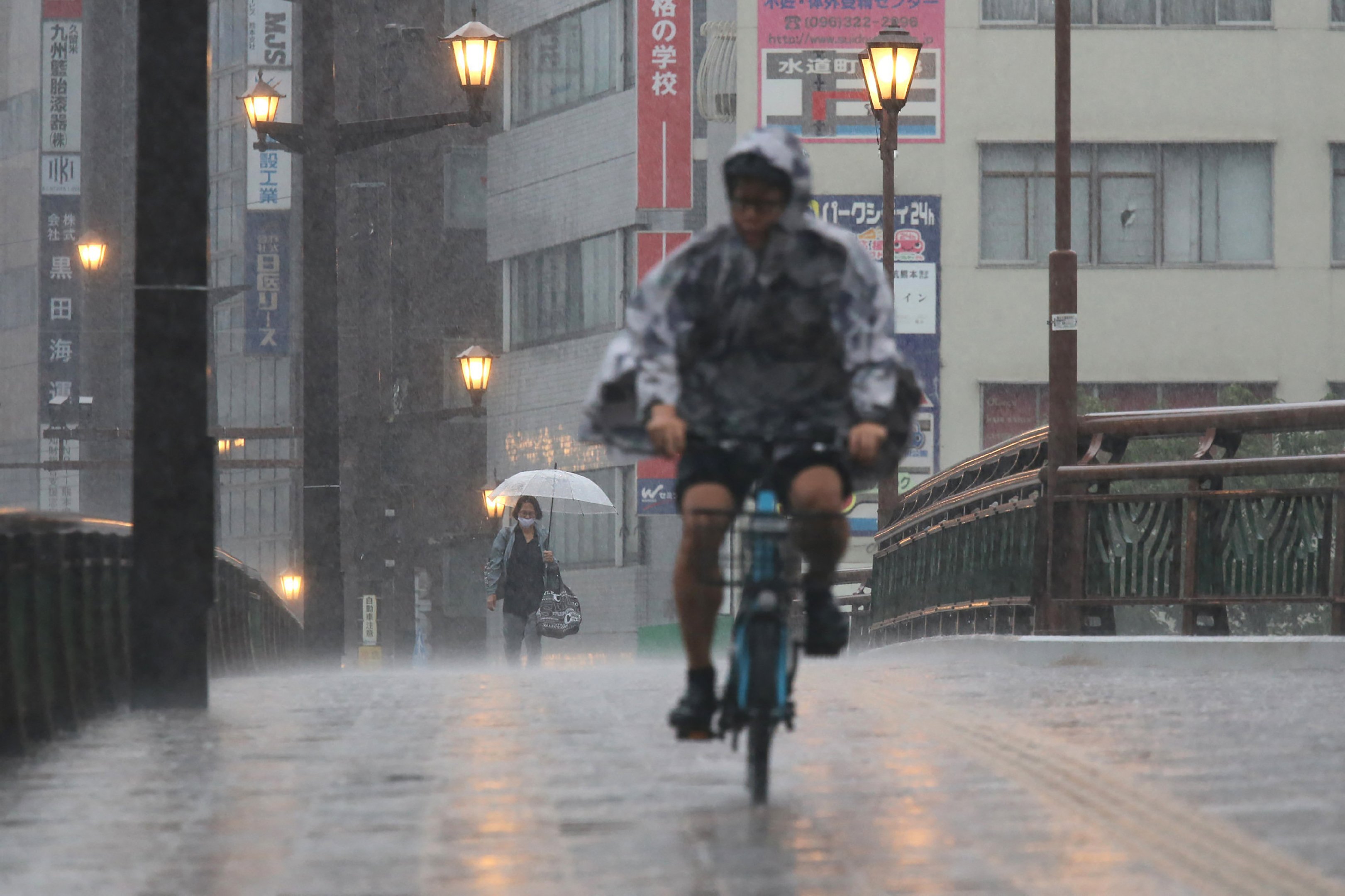 Chuvas intensas no Japão provocam desaparecimentos e alertas de evacuação em massa Chuvas no Japão: pessoas caminham e pedalam sob forte chuva na cidade de Kumamoto, no sudoeste do país, em 11 de agosto de 2025. (Foto: STR/JIJI Press/AFP/Getty Images)