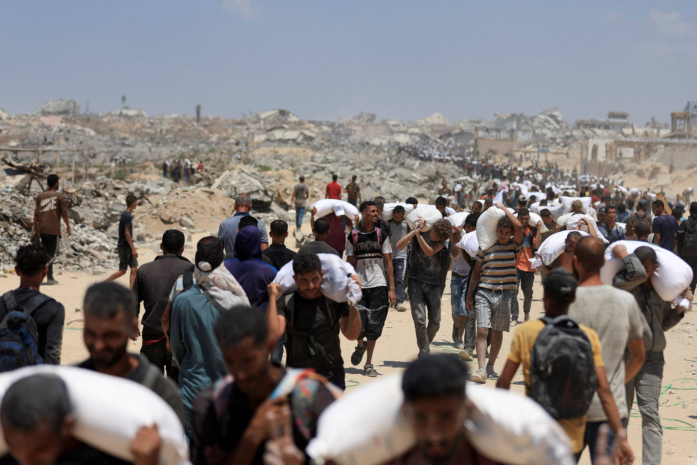Palestinos carregam suprimentos de ajuda que entraram em Gaza através de Israel, em Beit Lahia (Foto: Dawoud Abu Alkas/Reuters)