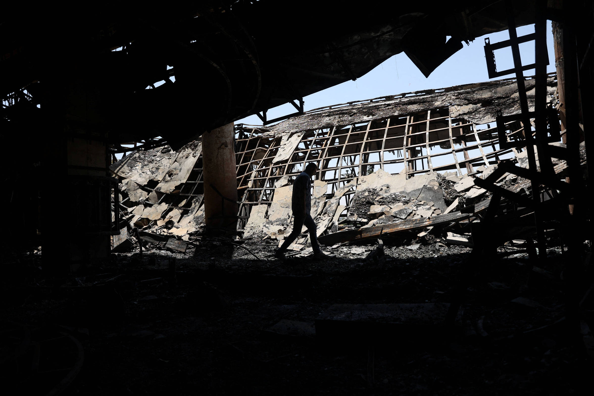 Guerra no Irã fortalece união entre a população, afirma professor de Fordow Homem caminha entre escombros de prédio destruído por bombardeio israelense em Teerã, capital do Irã (Foto: Majid Asgaripour - 19.jun.25/Reuters)