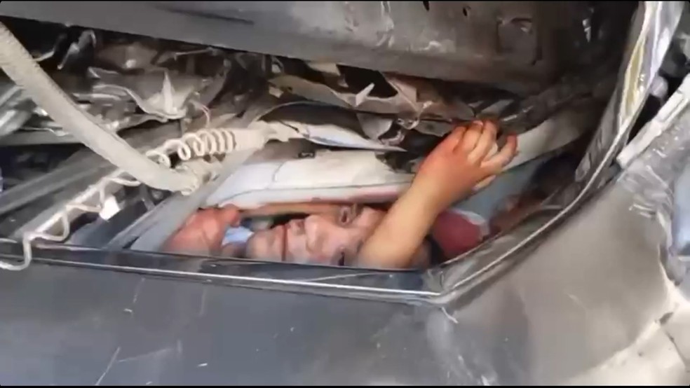 Carro é esmagado e mãe clama por ajuda ao filho preso nas ferragens Pedro, de apenas sete anos, coloca a mão para fora do carro logo depois do acidente que deixou cinco pessoas de uma mesma família em meio a ferragens. (Foto: Reprodução/TV Globo)