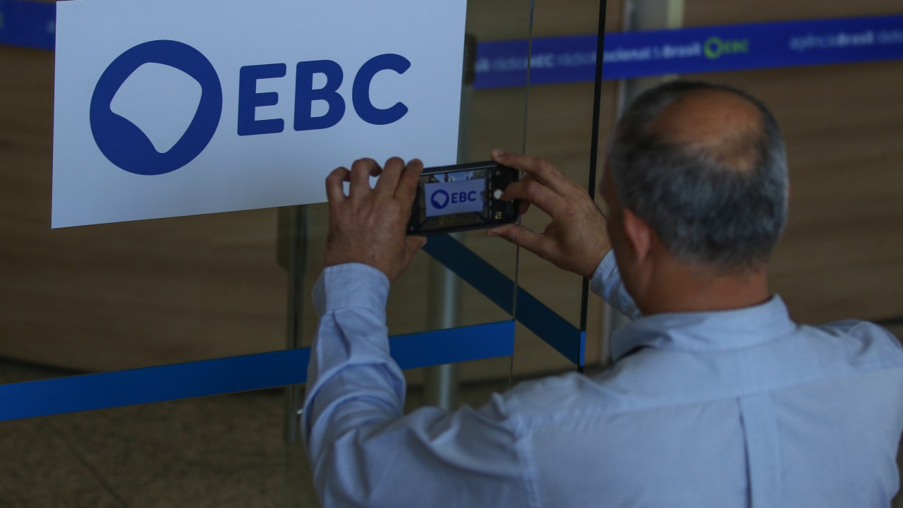Chefe da EBC renuncia ao cargo e provoca mudanças no governo Lula Homem fotografa a nova marca da Empresa Brasil de Comunicação (EBC), na entrada da empresa, em Brasília (Foto: José Cruz/Agência Brasil)