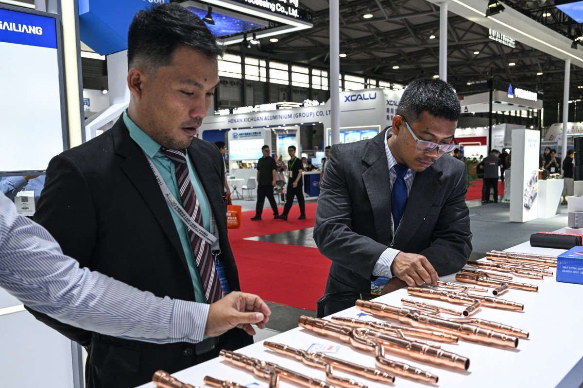 Visitantes verificam tubos de cobre em um estande durante a Feira Comercial Copper China 2025 (Foto: Hector RETAMAL / AFP)