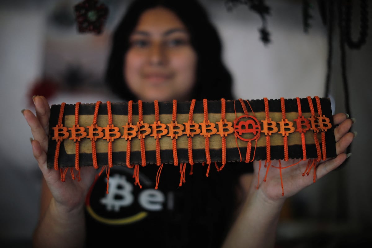 Uma mulher mostra brazaletes com temática de bitcoin à venda em Berlín, El Salvador, no dia 15 de julho de 2025. (Foto: José Cabezas/Reuters)