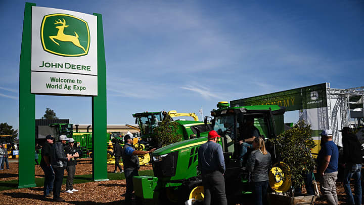 O logotipo da John Deere é exibido enquanto os participantes observam um trator utilitário 5105M no estande da Deere & Co. durante a World Ag Expo no International Agri-Center em Tulare, Califórnia, em 11 de fevereiro de 2025. (Foto: Patrick T. Fallon | AFP | Getty Images)