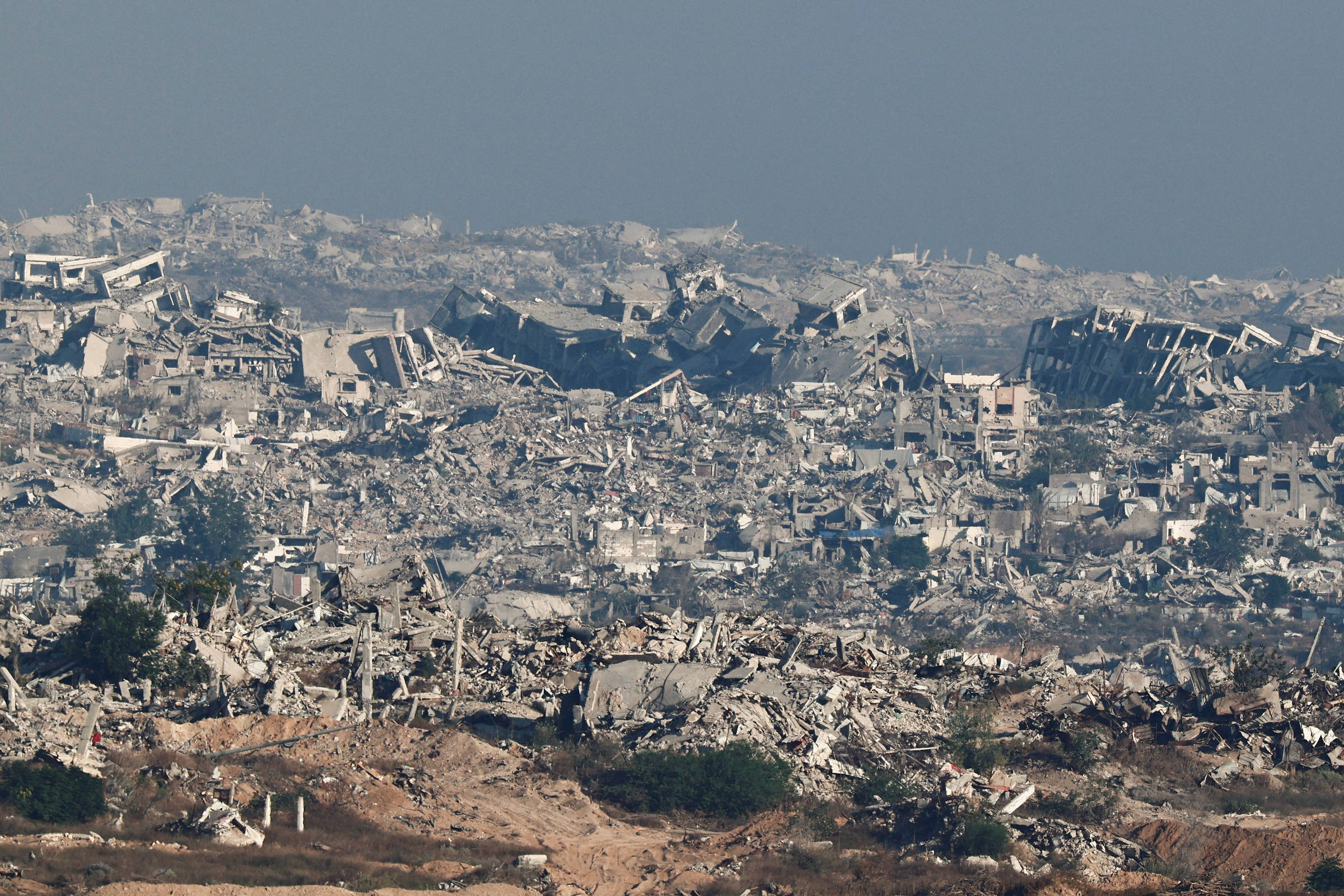 Governo propõe pagamento para palestinos deixarem a Faixa de Gaza em reconstrução Destruição dos edifícios no norte da Faixa de Gaza vista do lado israelense da fronteira (Foto: Amir Cohen/7.jul.25/Reuters)