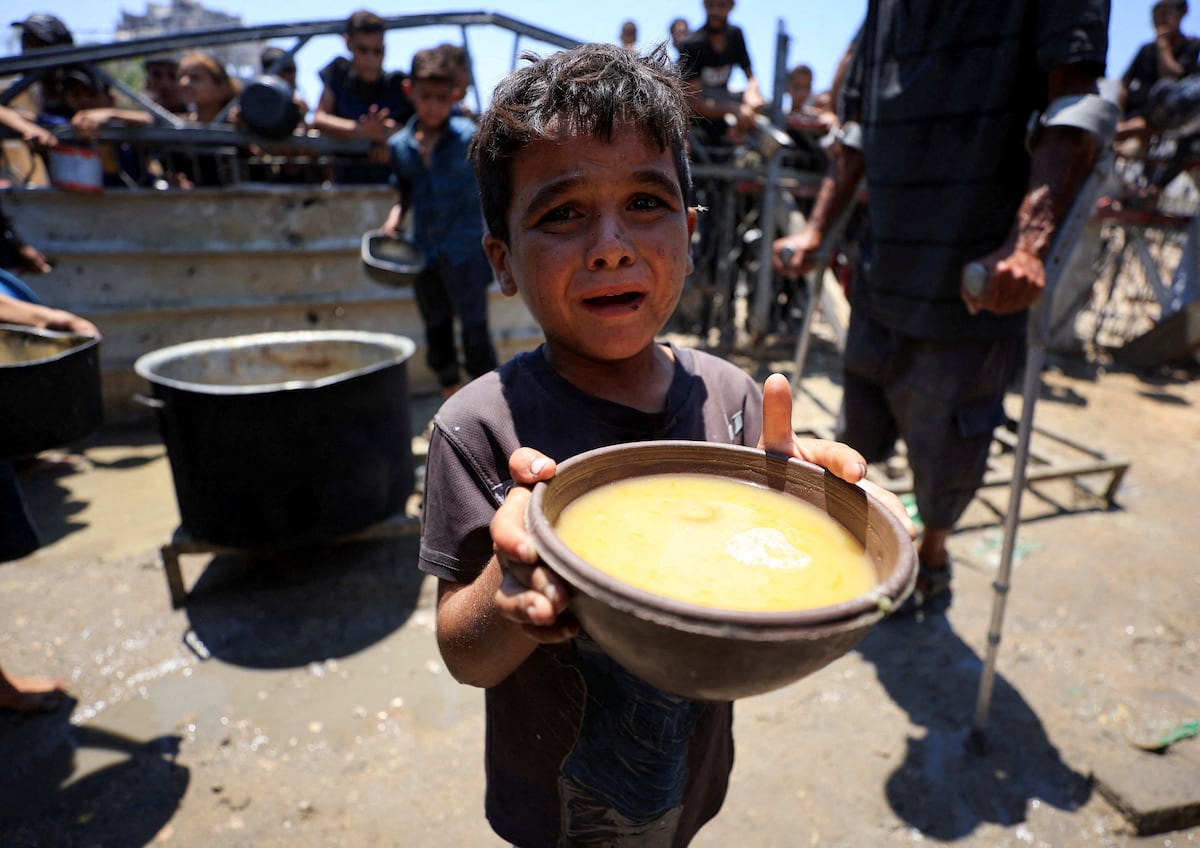 Um menino palestino segura um cuenco com comida recebida de um comedor de beneficência, em meio a uma crise de fome, na cidade de Gaza, este quinta-feira. (Foto: Dawoud Abu Alkas/REUTERS)