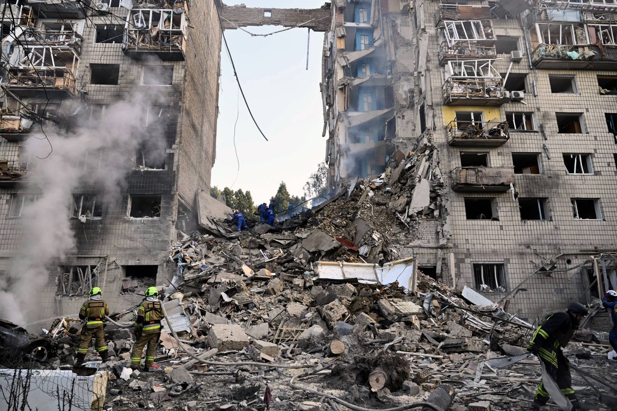 Socorristas ucranianos conduzem operação de buscas em destroços de edifício residencial bombardeado em Kiev (Foto: GENYA SAVILOV / AFP)