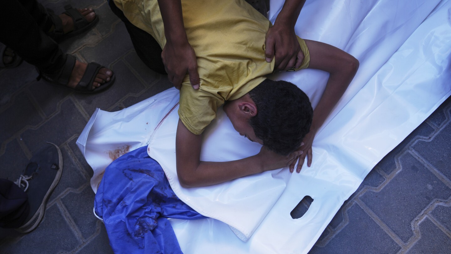 Um menino palestino chora sobre o corpo de seu amigo de 12 anos, Abdullah Ahmed, que foi morto em um ataque israelense que atingiu um ponto de distribuição de água potável, no Hospital Al-Awda em Nuseirat, no centro da Faixa de Gaza, no domingo, 13 de julho de 2025. (Foto: AP Photo/Abdel Kareem Hana)
