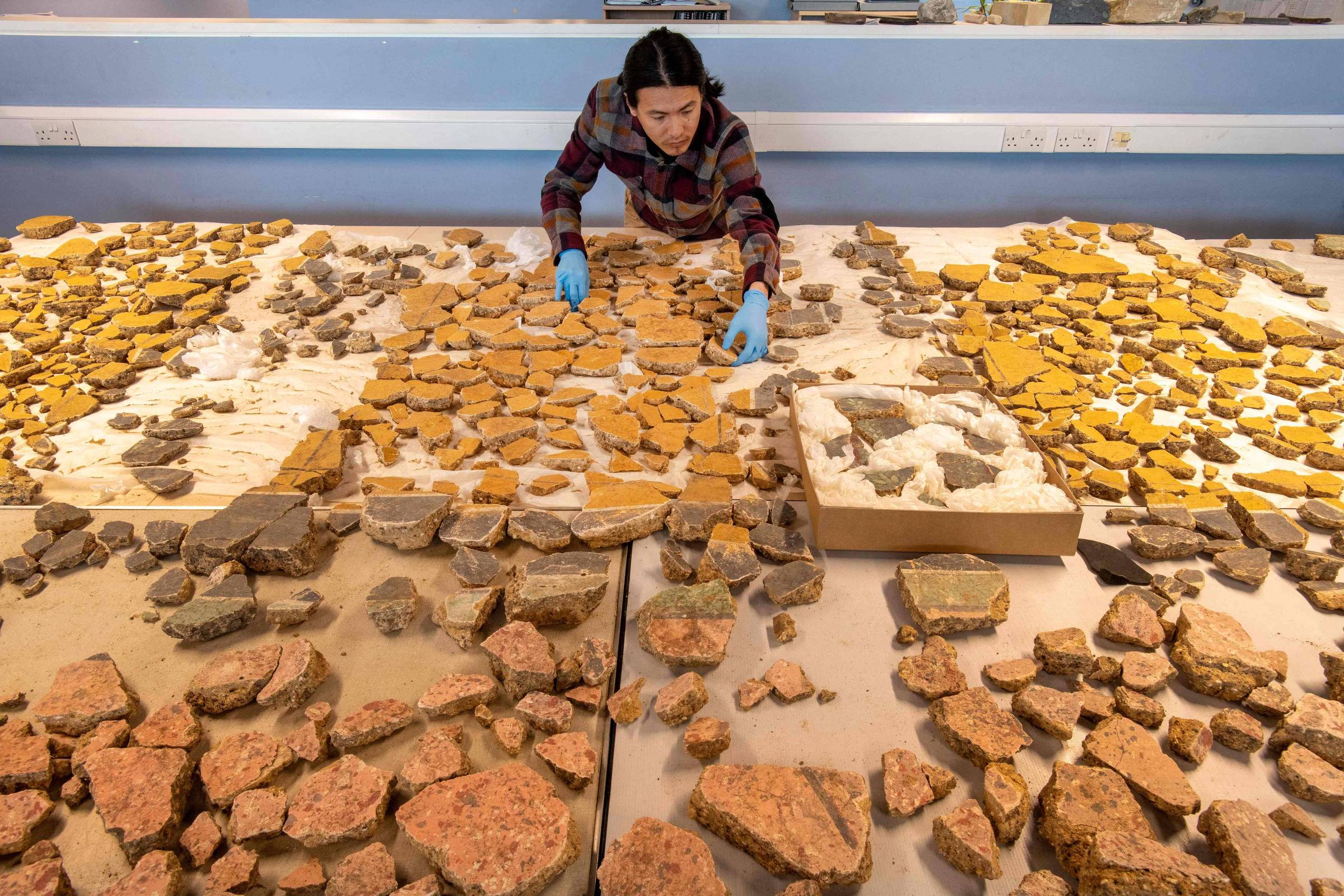 Arqueólogos reconstroem afrescos romanos de 1.800 anos com milhares de fragmentos O pesquisador Han Li tenta remontar afrescos romanos de mais de 1.800 anos (Foto: Museu de Arqueologia de Londres/AFP)
