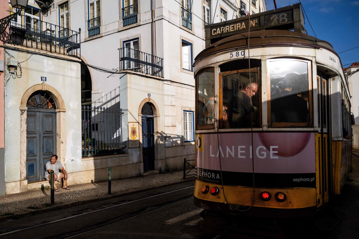 Bonde passa diante de homem sentado em uma calçada de Lisboa (Foto: Patrícia de Melo Moreira/AFP)