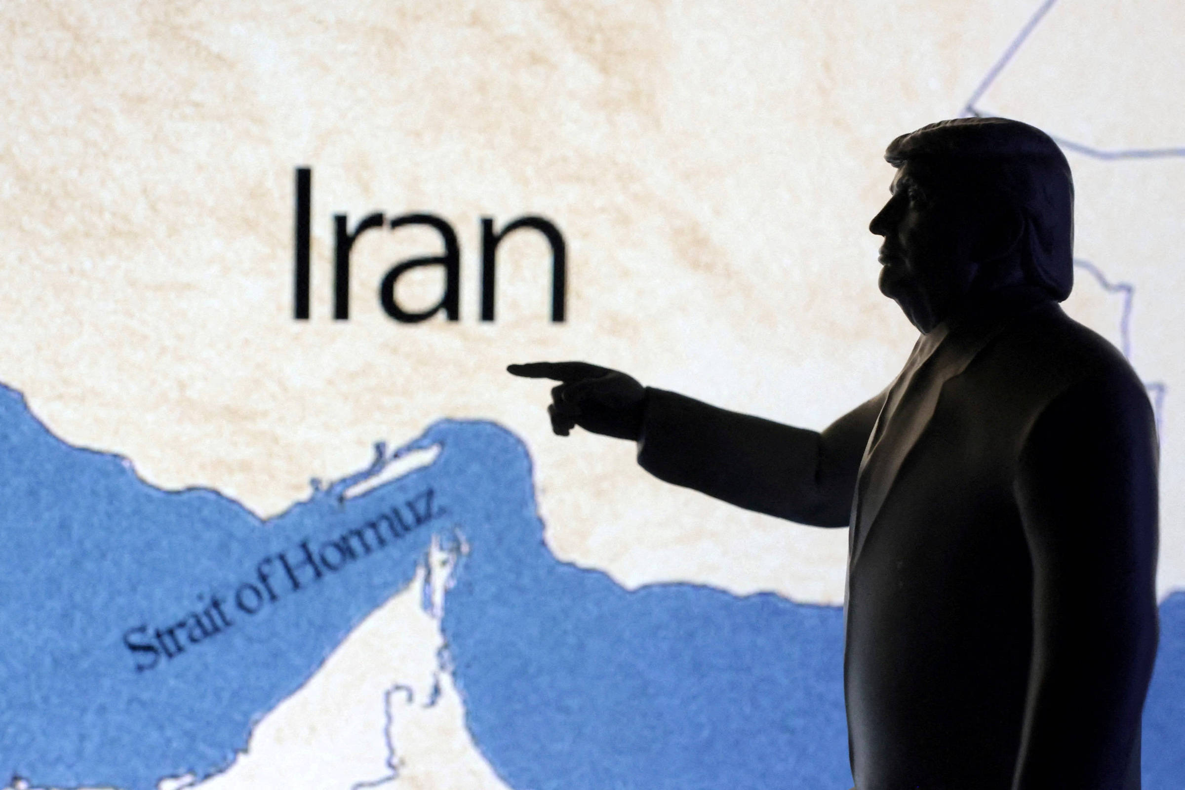 Negociadores de petróleo surpreendem e fazem preços caírem durante conflito Mapa mostrando o estreito de Hormuz e o Irã atrás de uma miniatura do presidente dos EUA, Donald Trump. O Irã promoveu nesta segunda (23) a retaliação pelo ataque americano contra a maior base dos EUA no Oriente Médio, no Qatar. (Foto: Dado Ruvic/Reuters)
