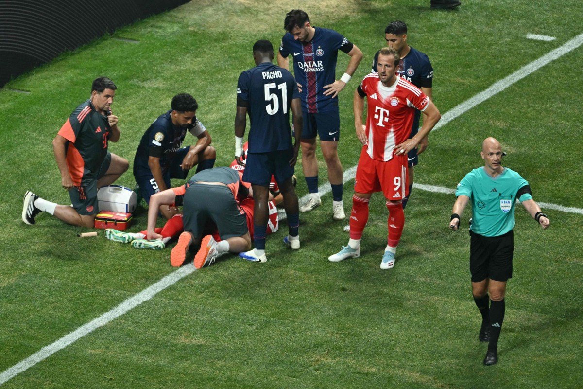 Musiala sofre grave lesão no Mundial de Clubes e preocupa Bayern de Munique Jogadores preocupados em volta de Musiala, caído no chão após grave lesão (Foto: ROBERTO SCHMIDT / AFP)