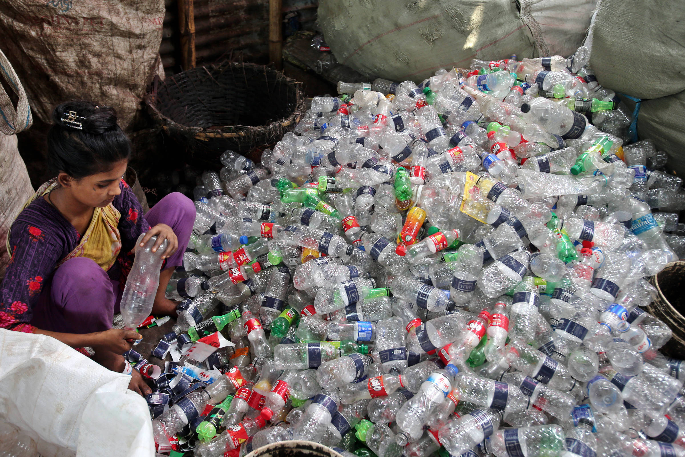 Mulher separa garrafas plásticas em Dhaka, Bangladesh. (Foto: Habibur Rahman - 19.mai.25/Xinhua)