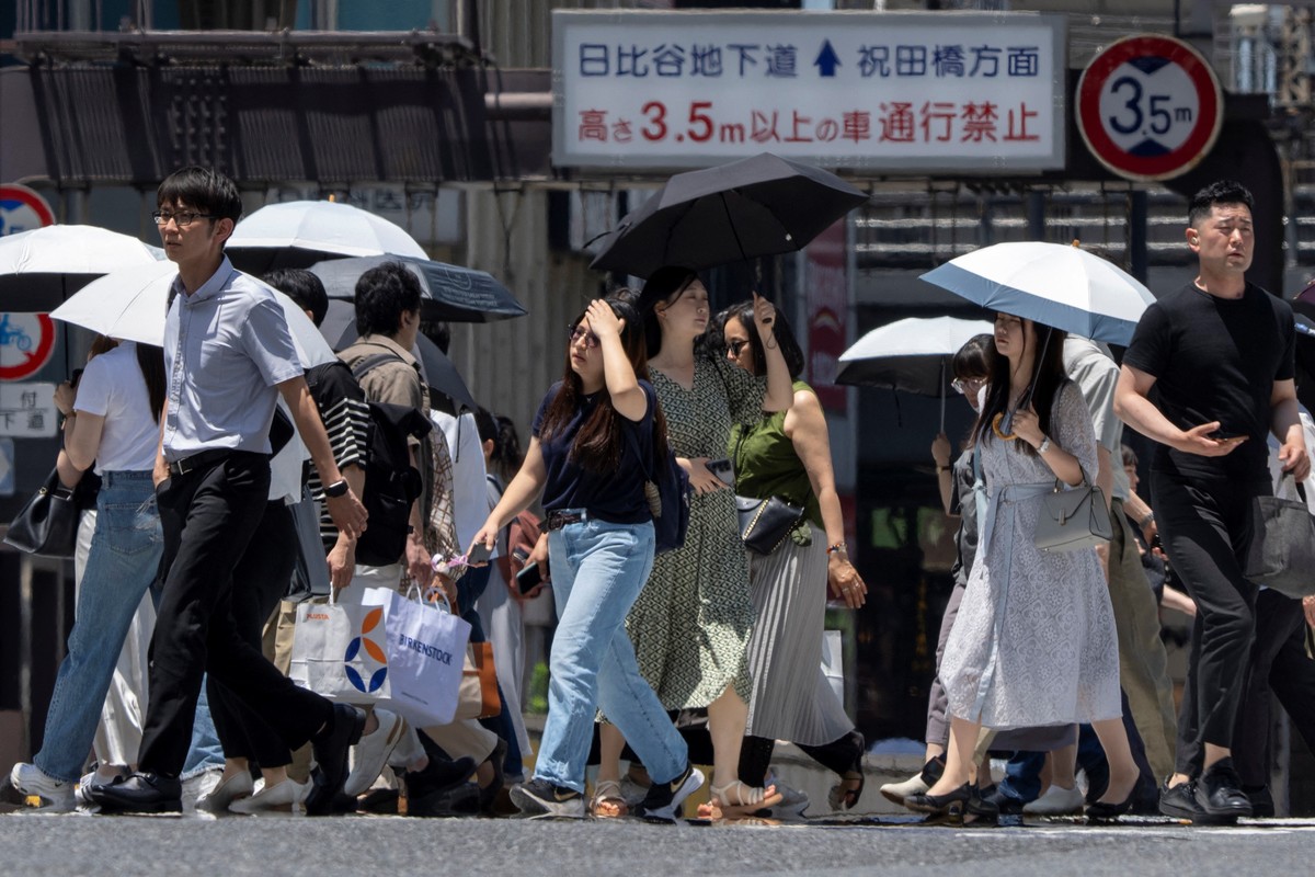 Japão enfrenta junho histórico com temperaturas recordes de calor Pessoas caminham por uma rua em um dia quente em Tóquio (Foto: Kazuhiro NOGI / AFP)