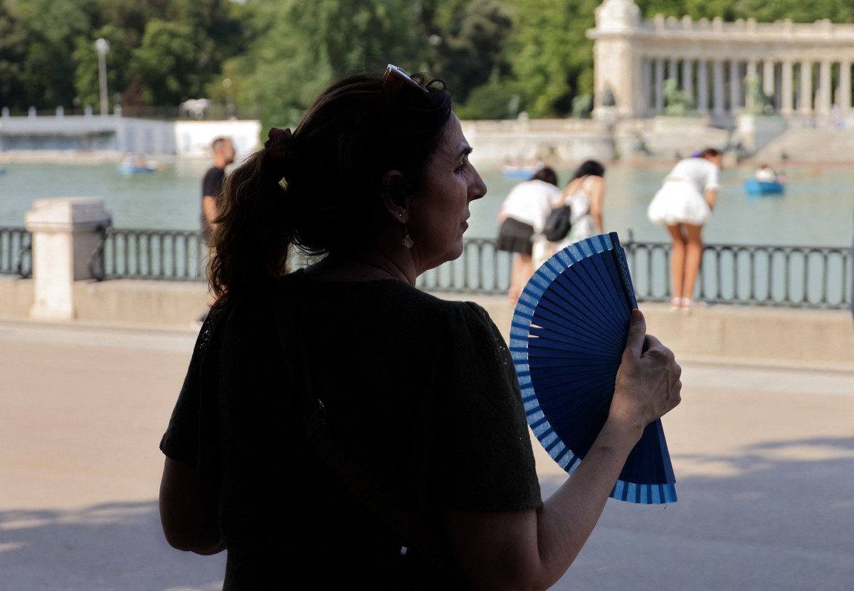 Península Ibérica registra novo dia de calor intenso com temperaturas de até 43 °C Mulher usa um leque para se refrescar em parque de Madri durante a primeira onda de calor do verão (Foto: Thomas Coex/ AFP)