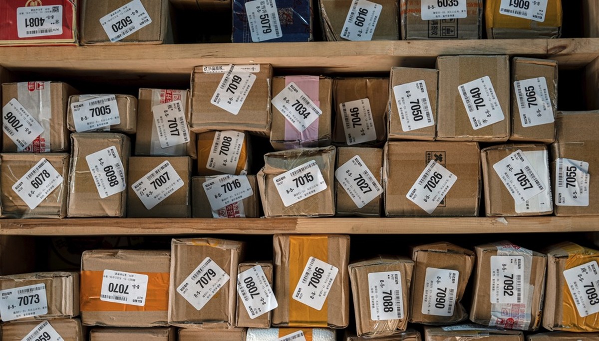 Tarifa elevada reduz importação de roupas dos EUA e queda de 40% em pacotes da China Pacotes em um centro de triagem de bairro em Pequim, China: remessas para os EUA recuam 40% em maio, mesmo em meio à trégua da tarifação dos EUA (Foto: Na Bian/Bloomberg)
