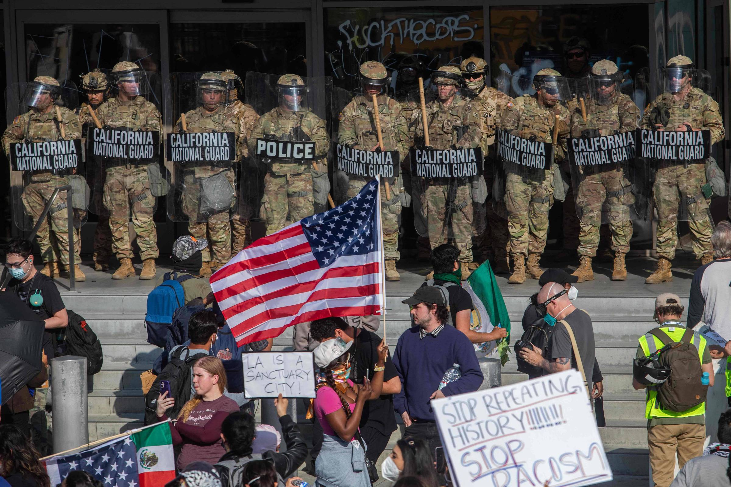 Manifestantes enfrentam membros da Guarda Nacional da Califórnia do lado de fora de um prédio federal, enquanto protestam contra operações federais de imigração, em Los Angeles (Foto: Apu Gomes - 9.jun.25/AFP)