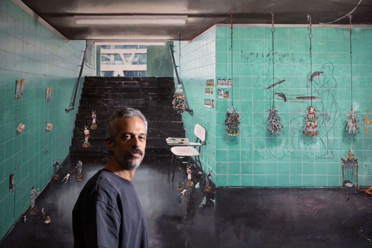 André Griffo expõe o lado sombrio da religião em suas novas pinturas André Griffo em frente à tela 'O vendedor de miniaturas' (2020) — Foto: Ana Branco