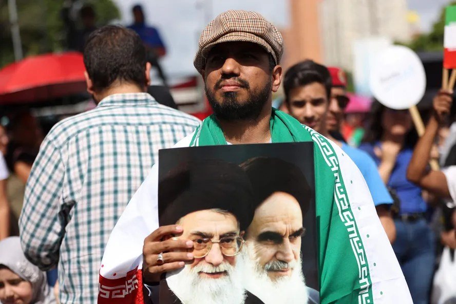 Efeitos do golpe de 1953 no Irã ainda alimentam conflitos atuais entre nações Manifestante segura foto com as imagens do líder supremo do Irã, Ali Khamenei, e do fundador da República Islâmica, aiatolá Ruhollah Khomeini (Foto: Pedro MATTEY / AFP)