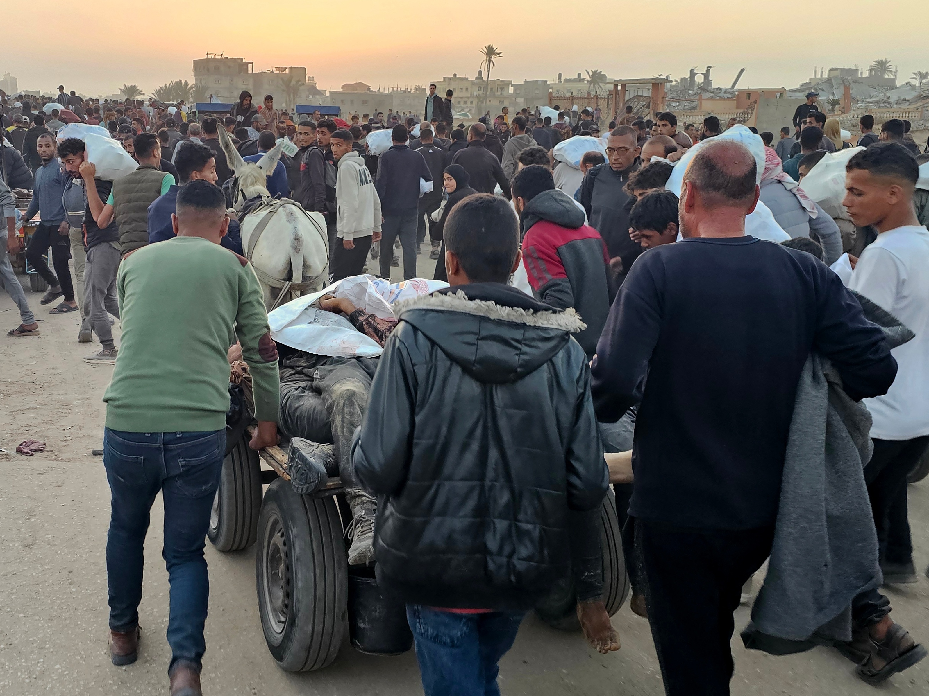Palestinos deslocados empurram carroça com corpos após ataque perto de um centro de distribuição de alimentos em Rafah, no sul da Faixa de Gaza, no início de junho (Foto: AFP)
