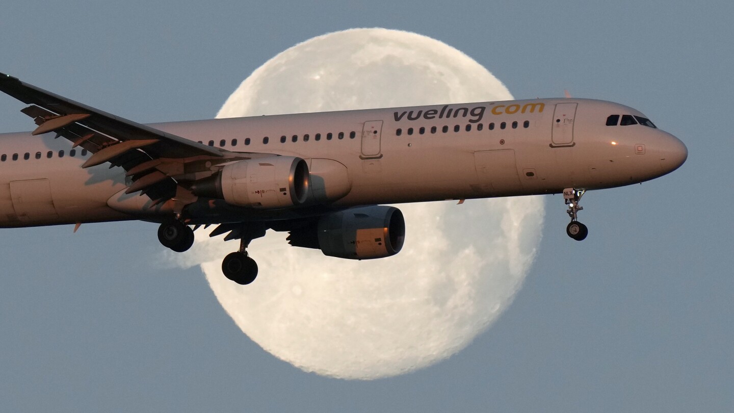 Um Airbus A321 da Vueling se aproxima para pouso em Lisboa ao amanhecer, enquanto a lua se põe ao fundo, 7 de fevereiro de 2023. (Foto: AP Photo/Armando Franca, File)