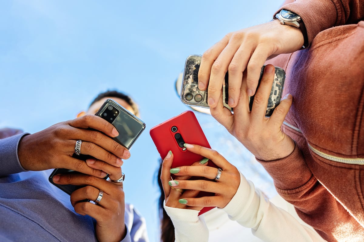 Três jovens usando o celular. Provavelmente, não para contar suas vidas nas redes sociais. (Foto: Xavier Lorenzo/Getty Images)
