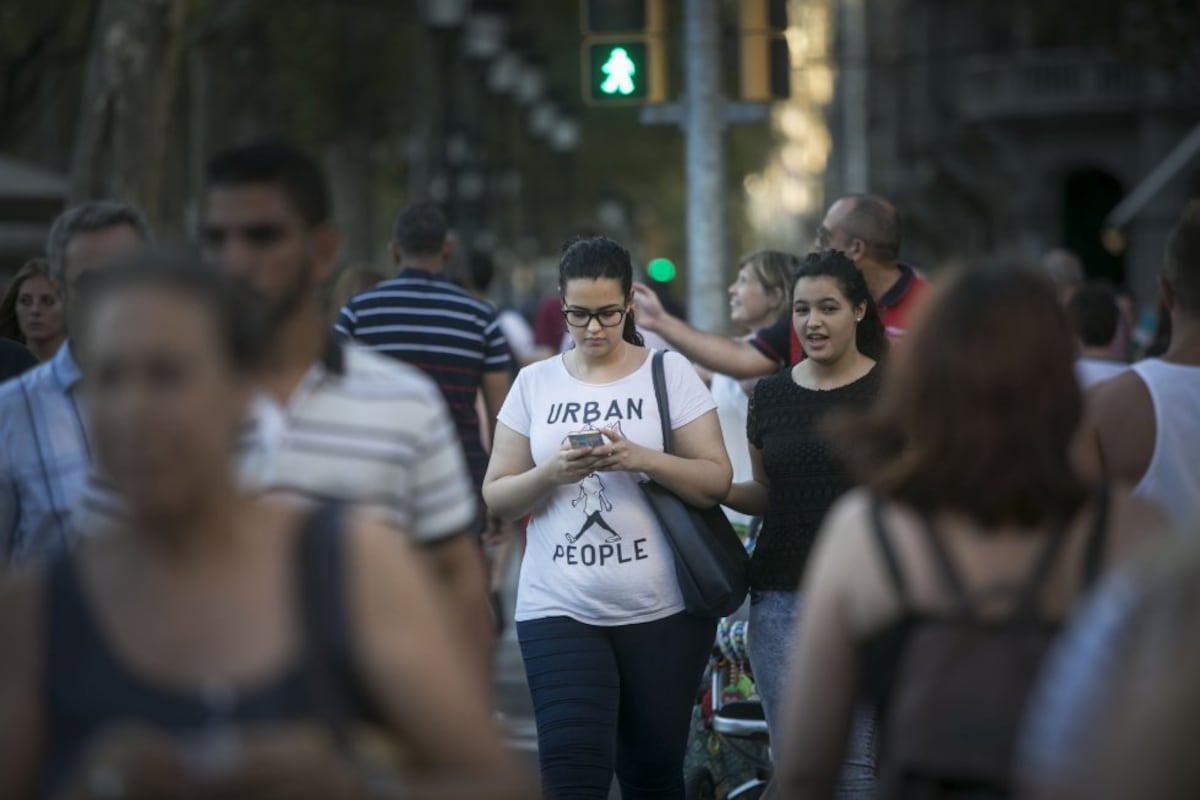 Uma mulher olha para o celular enquanto atravessa um passo de zebra. (Foto: Massimiliano Minocri)