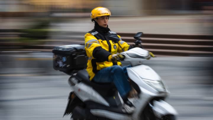 Guerra de preços na China oferece bebidas a R$ 1,50 com bilhões em subsídios Um entregador de comida da Meituan anda de patinete elétrico em Chongqing, China, em 29 de março de 2025. (Foto: Cheng Xin | Getty Images News | Getty Images)