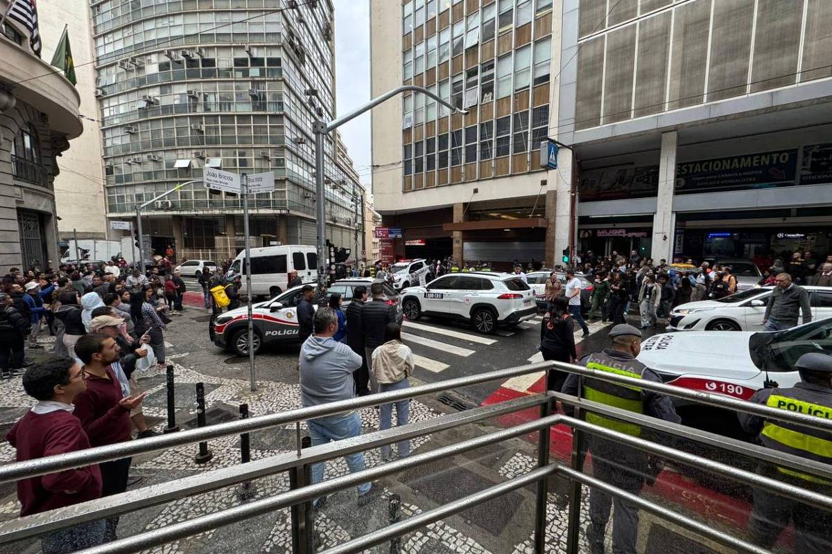 Curiosos observam movimentação da polícia na rua Boa Vista, no centro de São Paulo, onde uma mulher foi morta pelo ex-companheiro, que se matou em seguida na tarde desta sexta-feira (25) (Foto: Leitor)