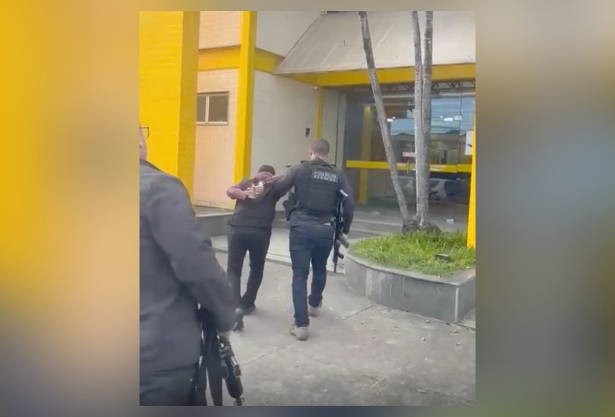 Padrasto é detido por extorsão sexual contra enteada com ameaças de divulgação de fotos Homem chega algemado à delegacia de Imbariê (Foto: Reprodução)