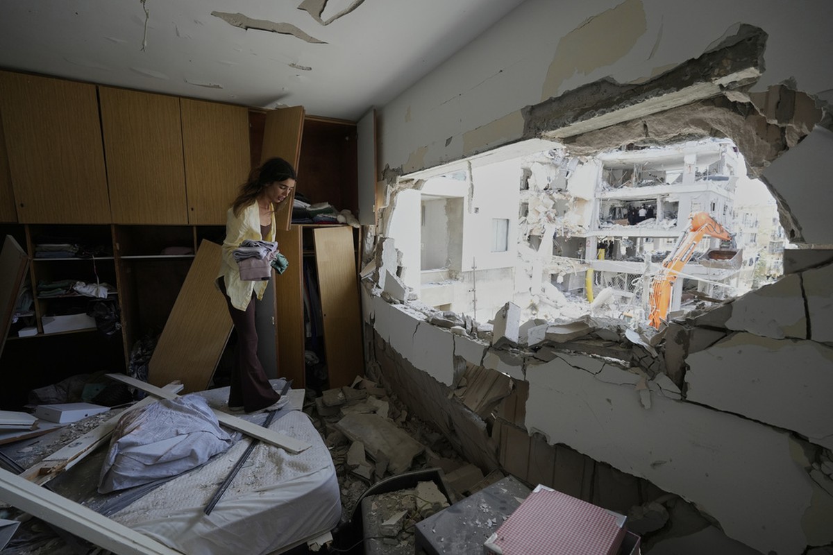Maryn Mahtiov recolhe pertences de seu apartamento no centro de Israel, depois que ele foi atingido por um míssil iraniano neste domingo (Foto: AP Photo/Baz Ratner)